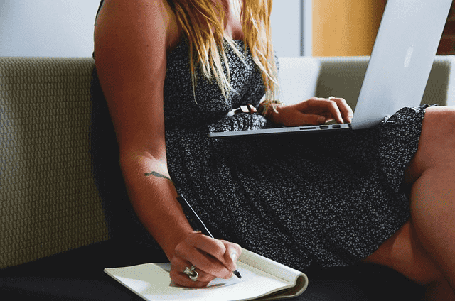 woman writing and being on her computer